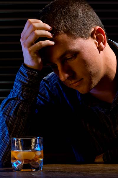мужчина сидит за столом со стаканом алкоголя